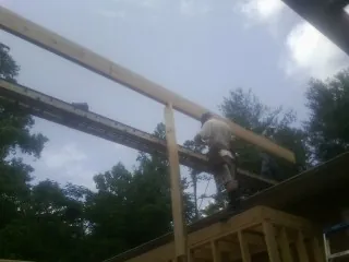 Carpenter setting a ridge beam over a new addition frame — Ice Dam Removal by Roofing Brothers in Saint Johns