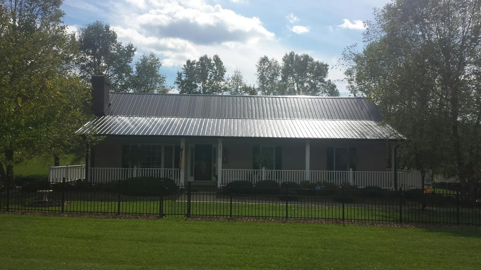 Gray metal roof on a brick ranch with a full width front porch — Gutter Guard Installation work by our crew in Saint Johns