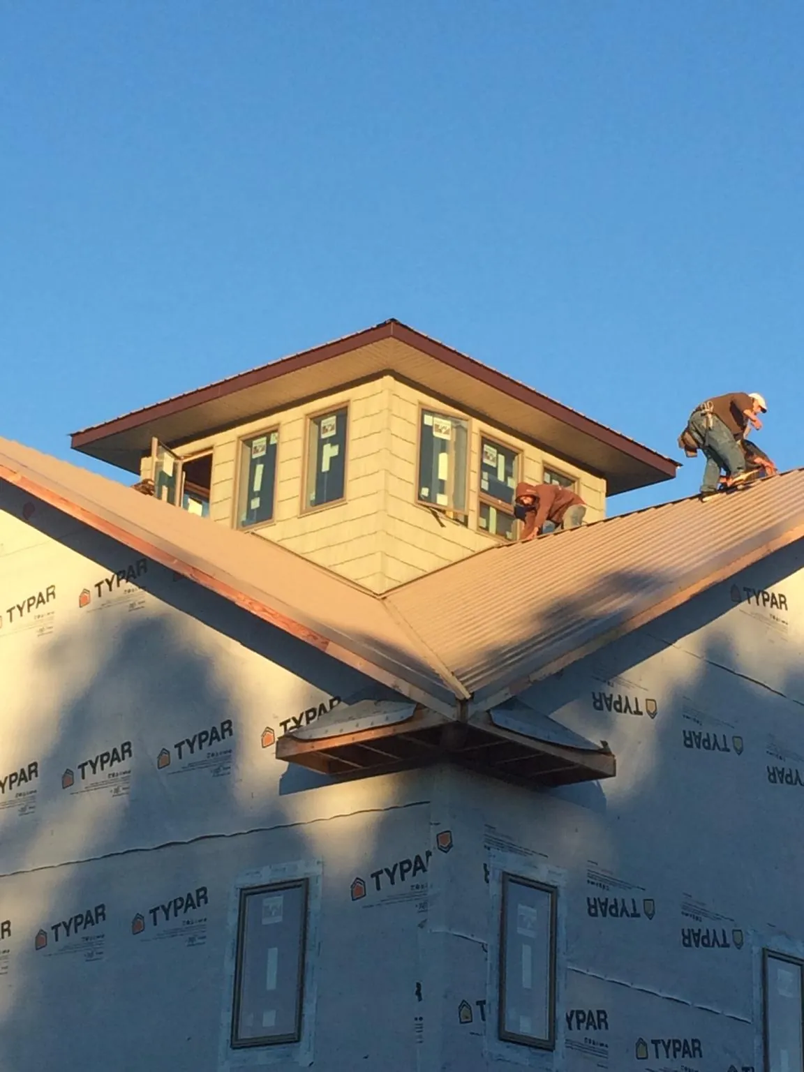 Roofers working around a rooftop cupola on a new metal roof at sunset — Roof Waterproofing in Saint Johns by Roofing Brothers